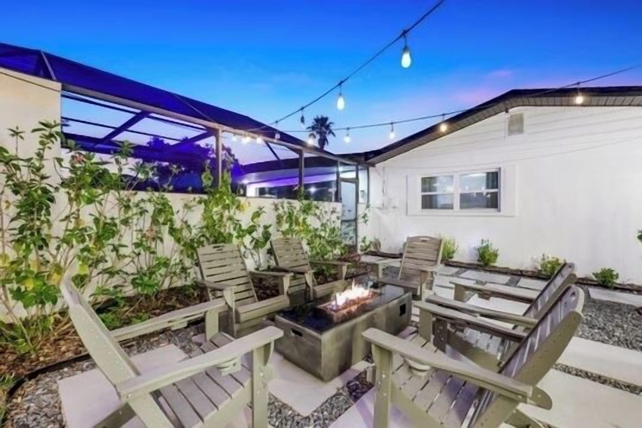 An outdoor patio with a fire pit, seating area, and string lights.