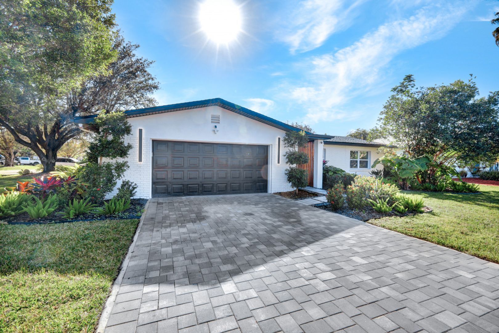 A single-story house with a garage, surrounded by a well-maintained lawn and various plants.