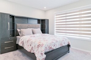 A bedroom with a bed, a wardrobe, and a window with blinds.