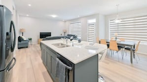 Una cucina moderna con isola centrale, elettrodomestici integrati e zona pranzo con tavolo e sedie.