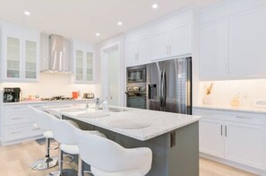 A modern kitchen with white cabinetry, a central island with a sink, and stainless steel appliances.