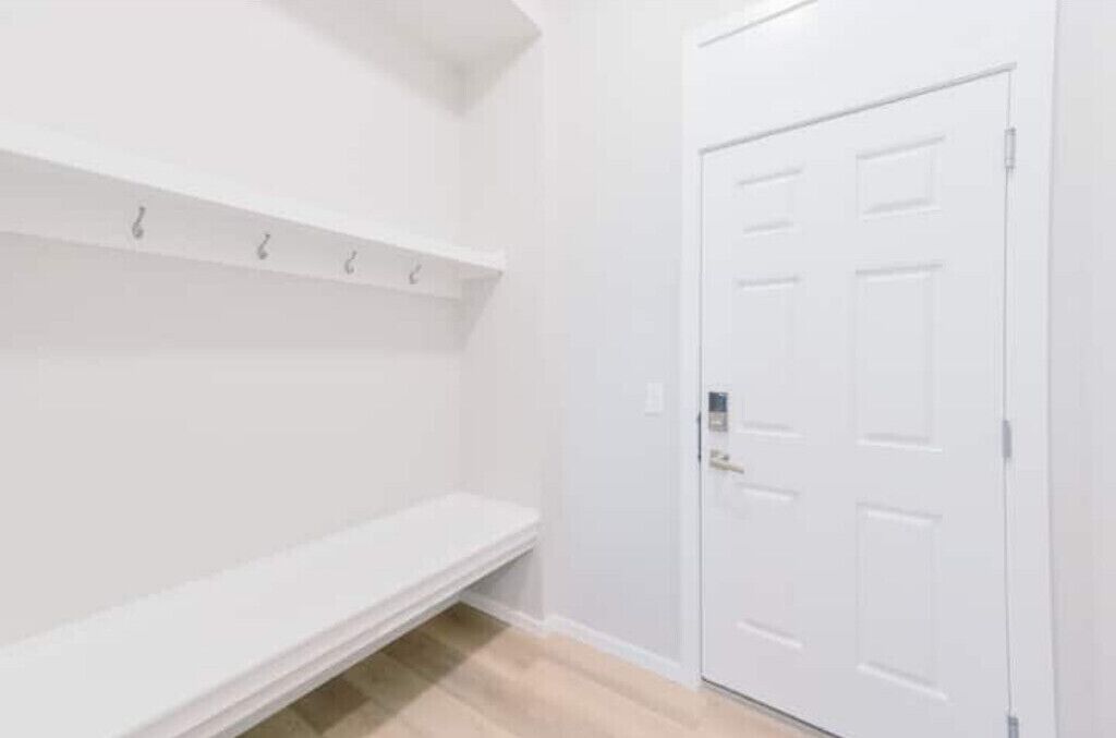 A white hallway with a door and a shelf.