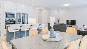 Una cucina moderna con mobili bianchi, forno integrato e un'isola grande con sgabelli da bar.