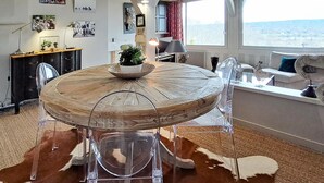 A round dining table with a wooden top and clear chairs, surrounded by a cowhide rug. - Beautiful apartment in Tourgéville with WiFi (Tourgéville)