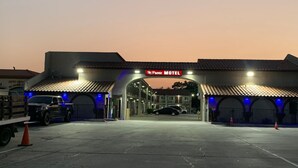 Ein Motel mit Ziegeldach, einer Beschilderung mit der Aufschrift 'La Puente Motel' und einem Parkplatz mit einigen Autos und einem Lastwagen.
