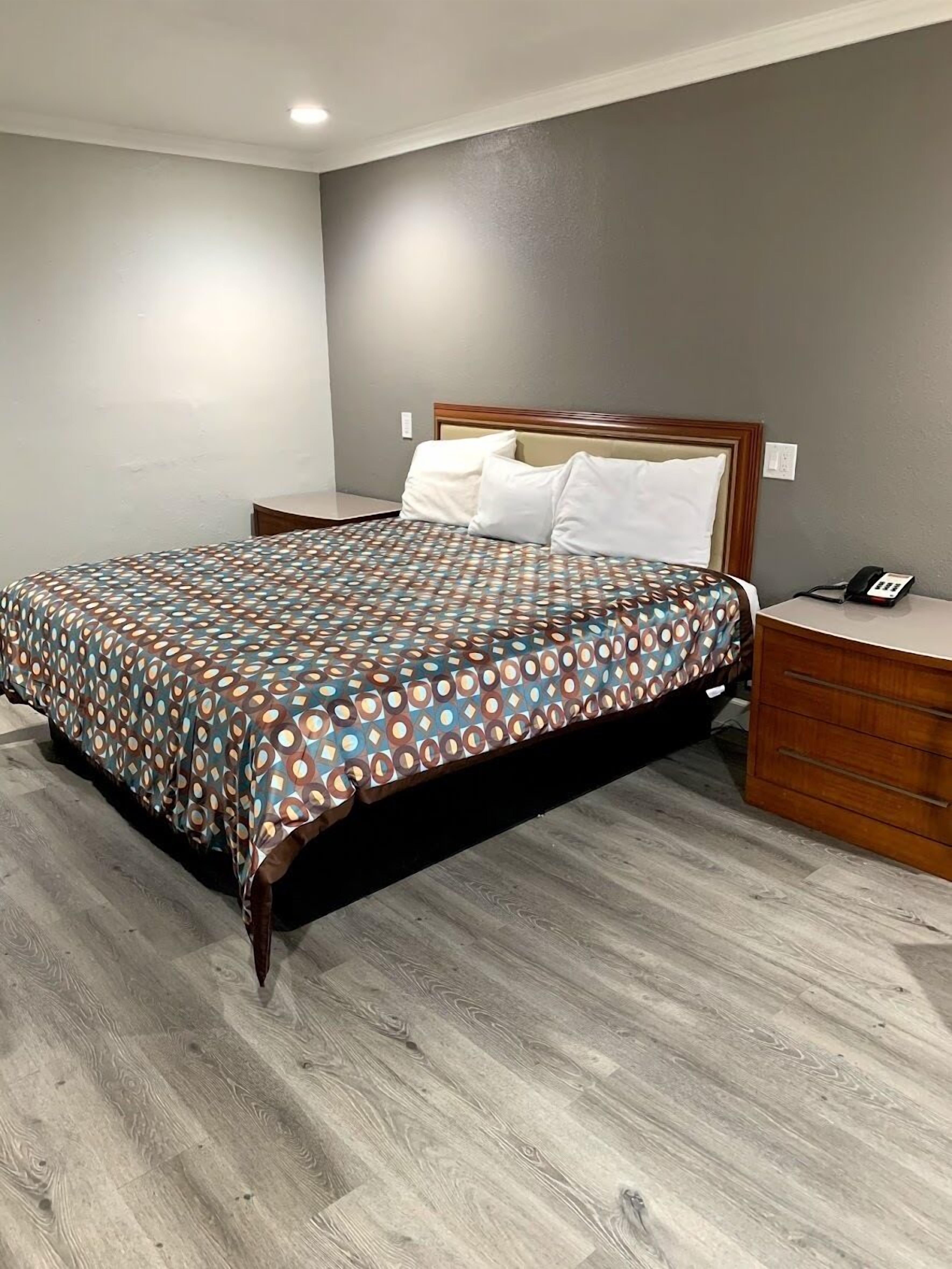 A hotel room with a bed, a bedside table, and a phone.