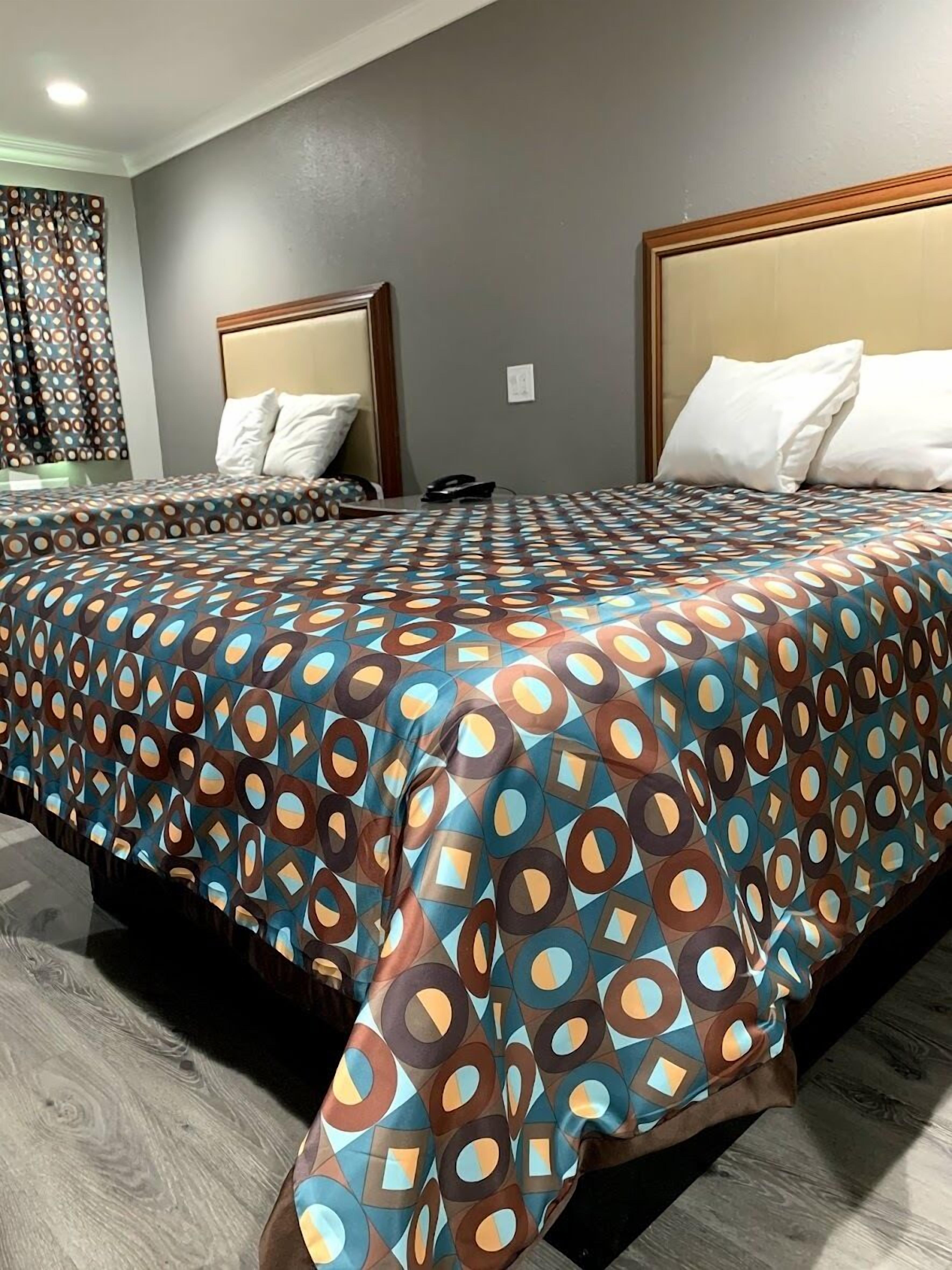 A hotel room with two beds, each with a headboard and white pillows.