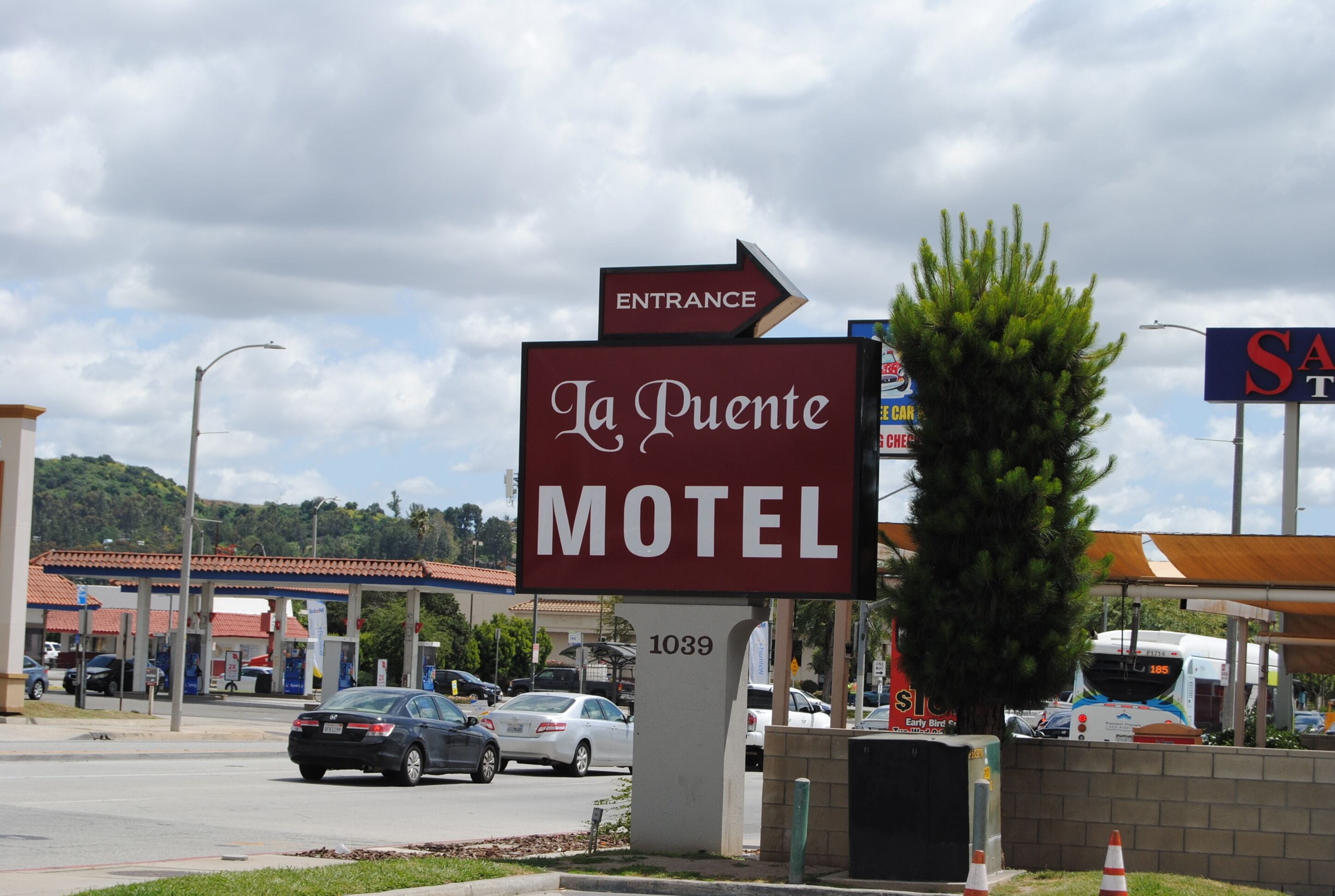 Letrero de motel con una flecha indicando la entrada, el número '1039' y una señal parcial que muestra la letra 'S'.
