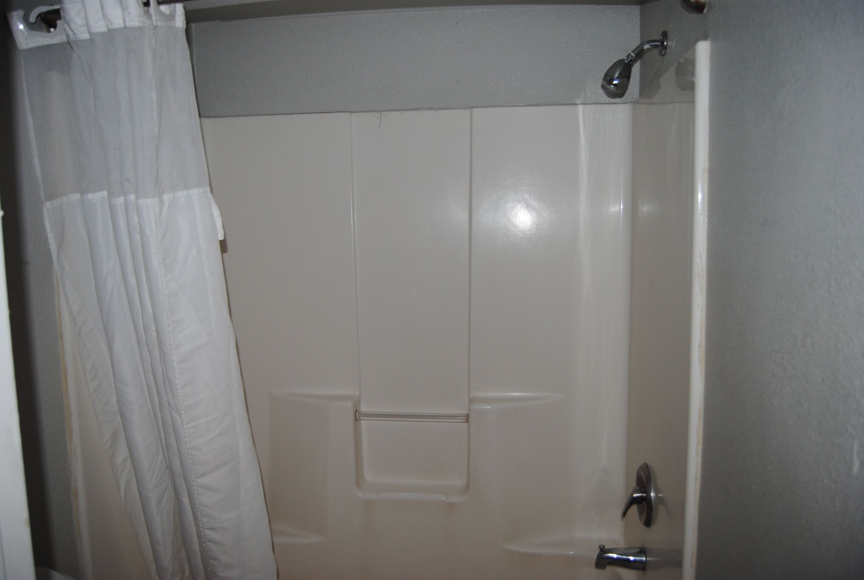 Un baño con cortina de ducha blanca, bañera y retrete.