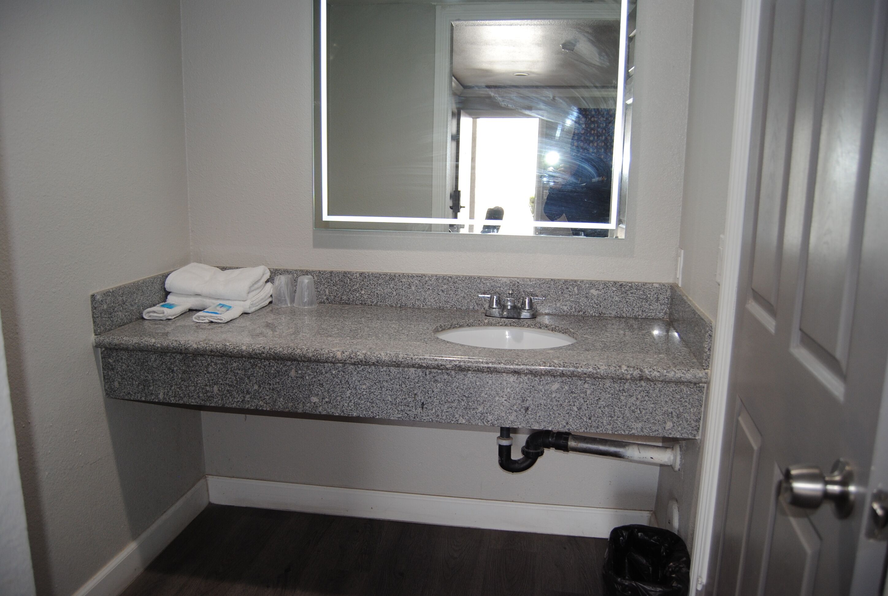 Une salle de bain avec un comptoir en granit, un lavabo et un miroir.