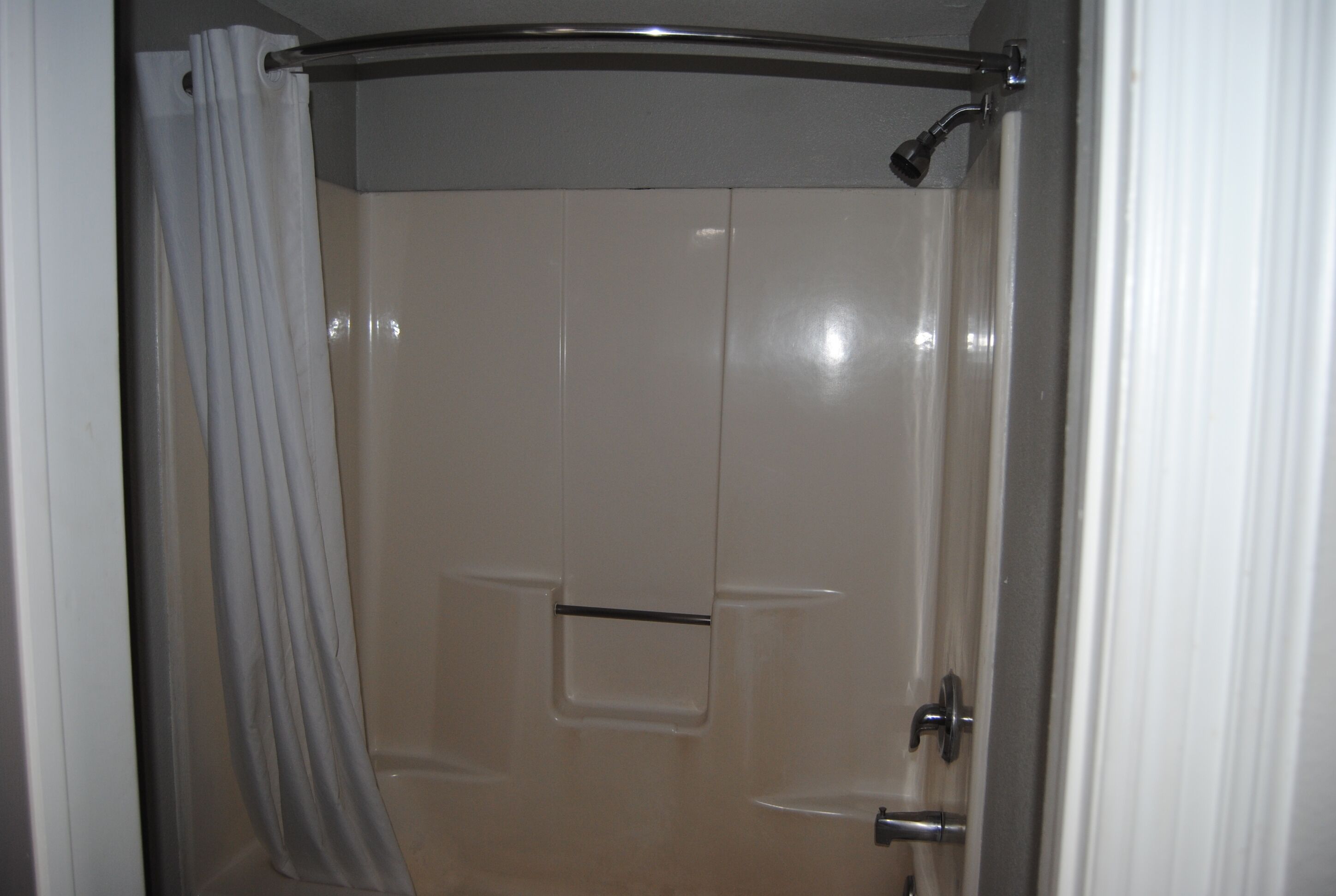A bathroom with a shower, a door, and a curtain.