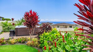 A well-maintained garden with various plants and a hot tub in a residential area with houses in the background. - Ocean Views|Beach 6 Min|Private Hot Tub|Gated|BBQ (Waianae)
