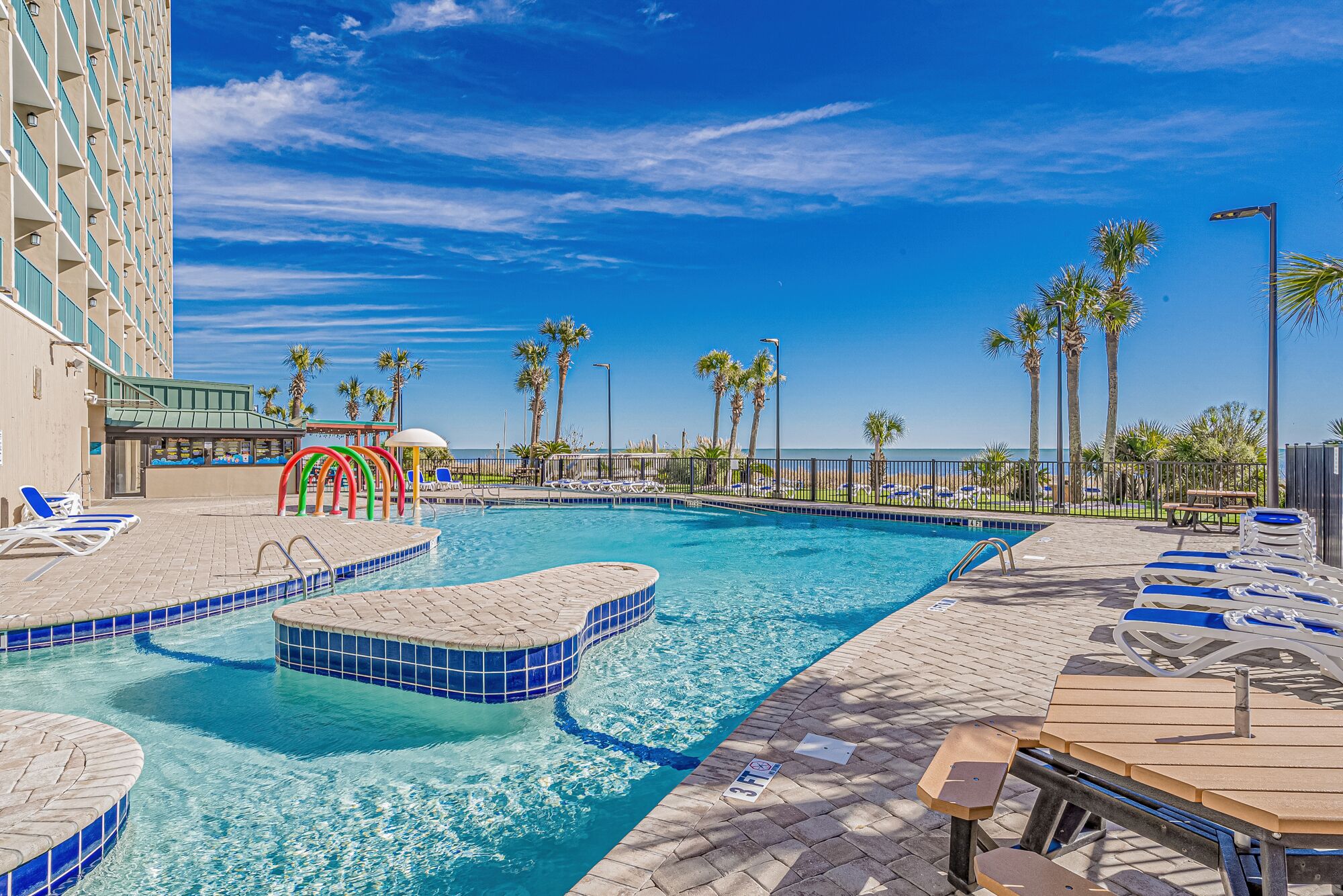 A swimming pool with lounge chairs and a view of the ocean.