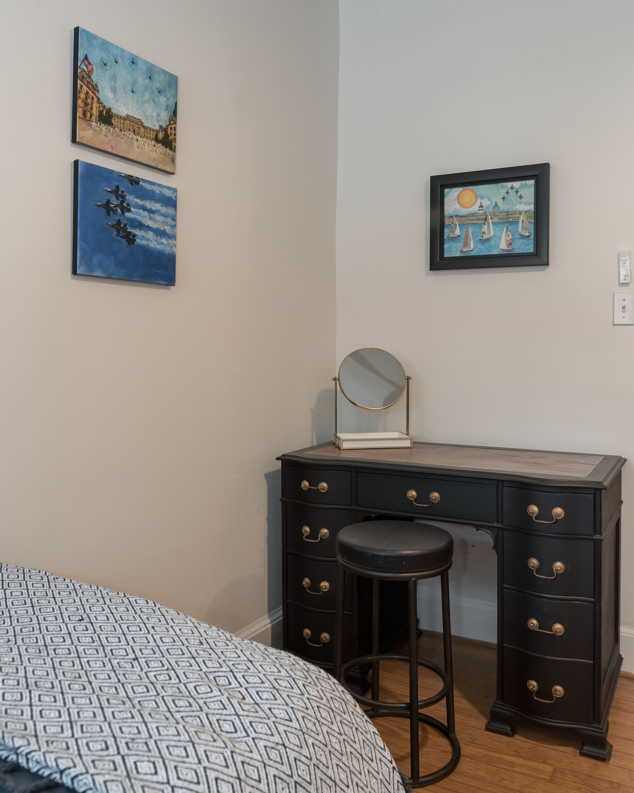 A bedroom with a bed, a dresser with drawers, a mirror, and two paintings on the wall.