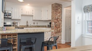 A kitchen with white cabinets, a granite countertop, and a brick column. - Walk to the Naval Academy and Historic Annapolis.  Private parking at the home. (Annapolis)