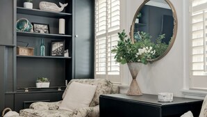 A room with a sofa set, a black console table, a large mirror, and a bookshelf with decorative items. - Walk to the Naval Academy and Historic Annapolis.  Private parking at the home. (Annapolis)
