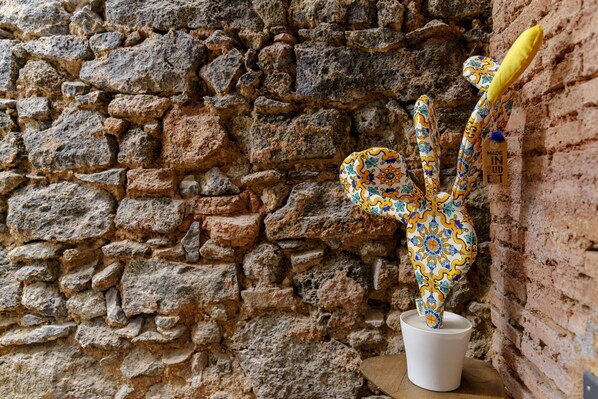 A cactus sculpture against a stone wall. - Lava rock formation in the center (Catania)