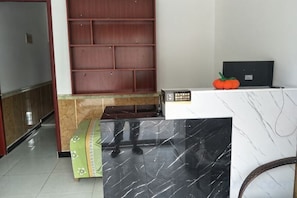 A reception area with a marble counter, a wooden panel wall, and a bench. - Jiaze Hotel (Ganquan)