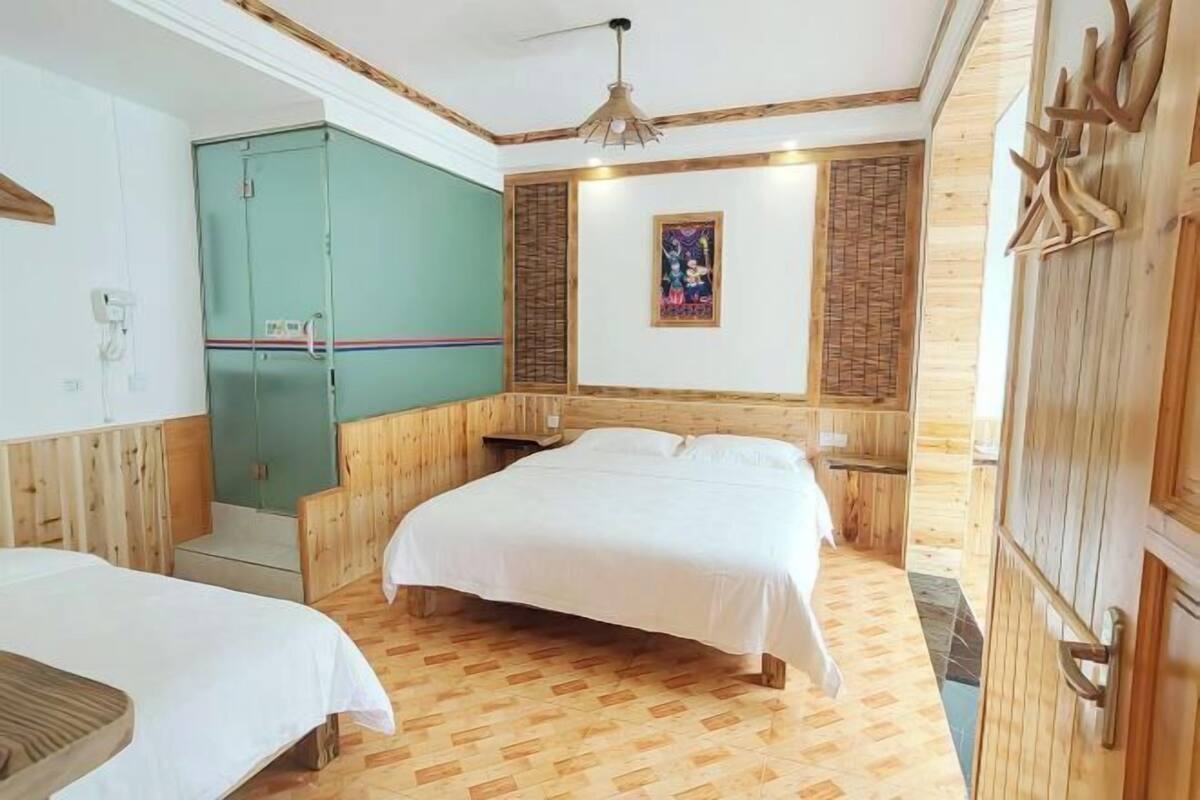 A room with two beds, wooden walls, a green cabinet, and a ceiling fan.