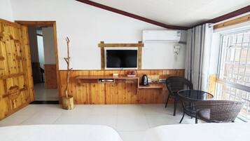 A room with a wooden wall, a TV mounted above a wooden counter, a chair, and a bed.