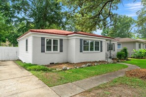 A single-story house with a red roof, white siding, and a front porch.
