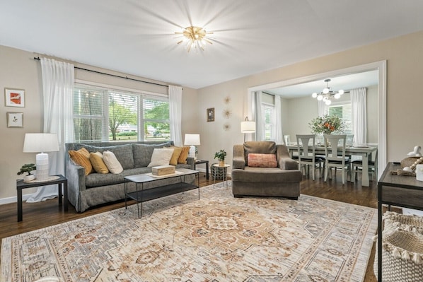 A living room with a sofa, armchair, coffee table, and a patterned rug.