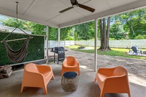 A covered patio area with outdoor seating, a grill, and a hammock.