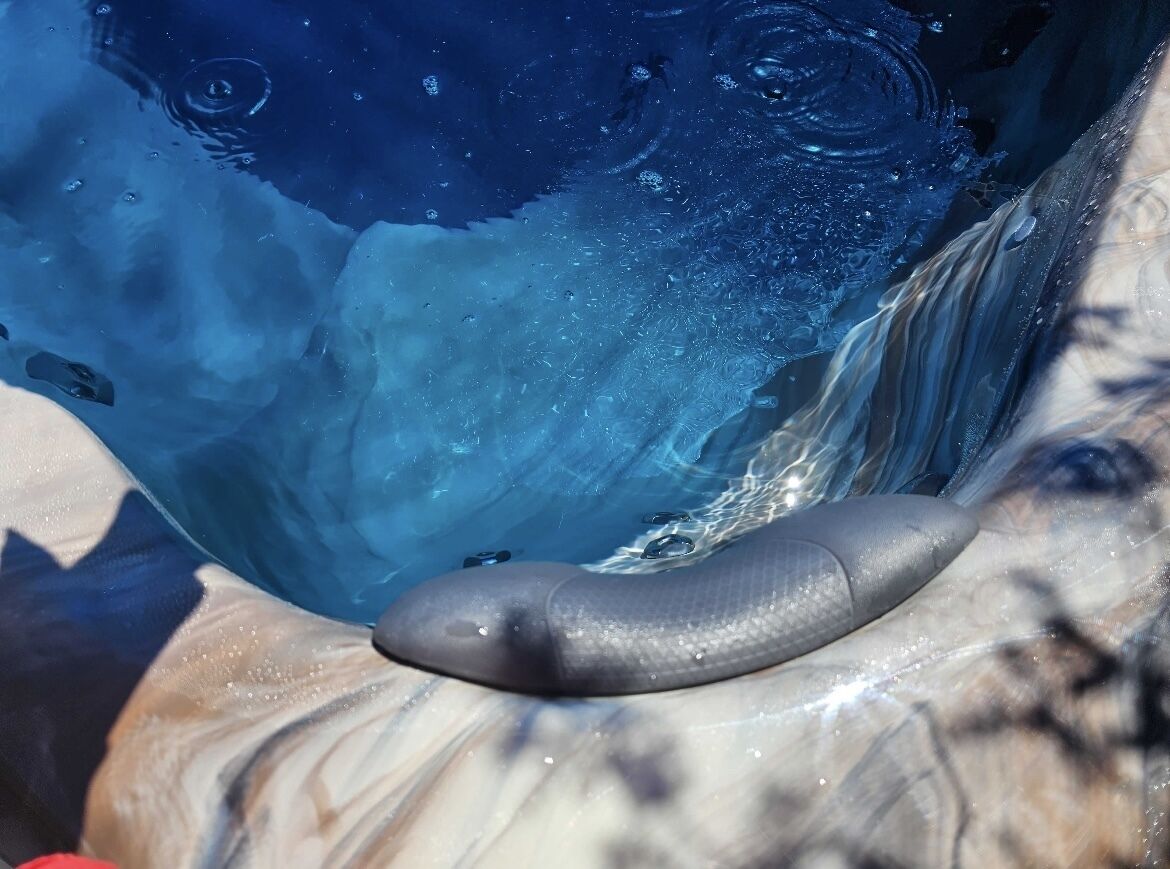 A pool with clear water and a dark-colored object, possibly a pool noodle, near the edge.