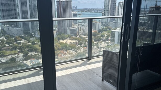 Un intérieur moderne avec une grande fenêtre donnant sur un paysage urbain, avec notamment des immeubles de grande hauteur et un chantier de construction.