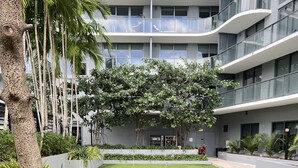Un bâtiment moderne doté d’une cour intérieure agrémentée d’une pelouse bien entretenue, de diverses plantes et d’un palmier.