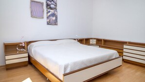 Et soveværelse med en seng med træramme, et natbord med lampe og en vægmonteret hylde.