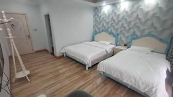 Habitación de hotel con dos camas individuales, piso de madera, un adorno en la pared y una puerta con un cartel.