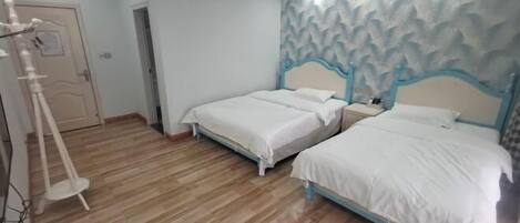 Une chambre d’hôtel avec deux lits simples, un plancher en bois, un mur décoratif et une porte ornée d’une affiche.