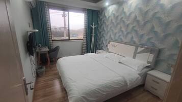 Un dormitorio con cama, mesita de noche y escritorio con silla.