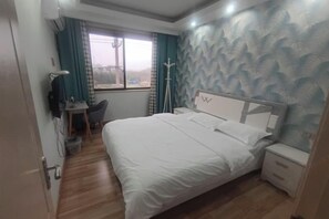 A bedroom with a bed, bedside table, and a desk with a chair. - Xinchang Yunqi Small Building House (Xinchang)