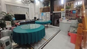 A hotel lobby with two round tables covered with blue tablecloths, a television, a reception desk, and a decorative plant. - Xinchang Yunqi Small Building House (Xinchang)