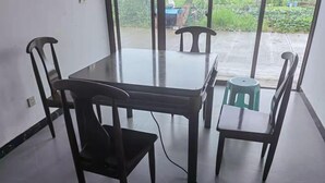 A dining area with a glass-top table, four wooden chairs, and a small stool. - Xinchang Yunqi Small Building House (Xinchang)