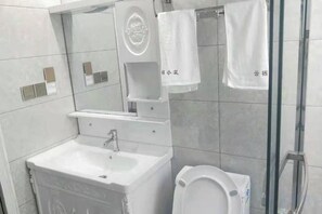 A bathroom with a sink, toilet, and a glass shower enclosure. - Xinchang Yunqi Small Building House (Xinchang)