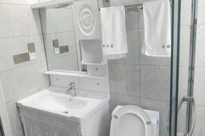 A bathroom with a sink, toilet, and a glass shower enclosure. - Xinchang Yunqi Small Building House (Xinchang)