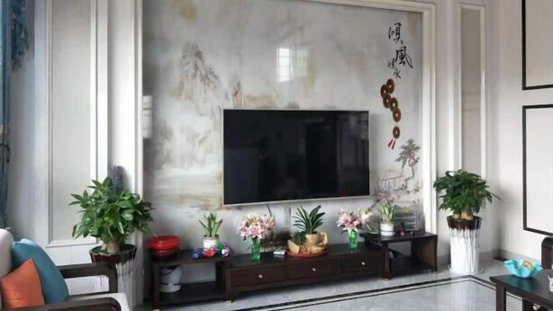 A living room with a large flat-screen TV mounted on a marble wall, a dark wooden console table with decorative items, and two potted plants. - Xinchang Yunqi Small Building House (Xinchang)