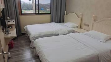 A hotel room with two beds, a desk with a computer, and a window with a view.
