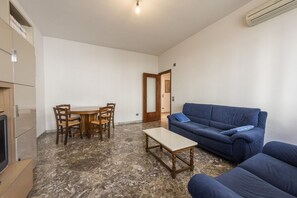 Una habitación con una mesa de comedor, sillas, un sofá y un televisor.