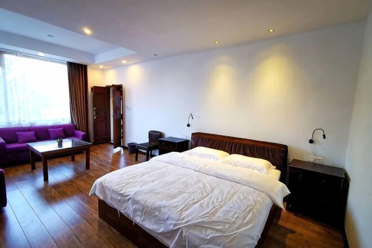 Una habitación de hotel con una cama grande, un sofá, un escritorio y un armario.