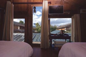 A room with two beds, a TV, and a view of traditional buildings outside. - Baisha No. 66 Post Station (Yulong)