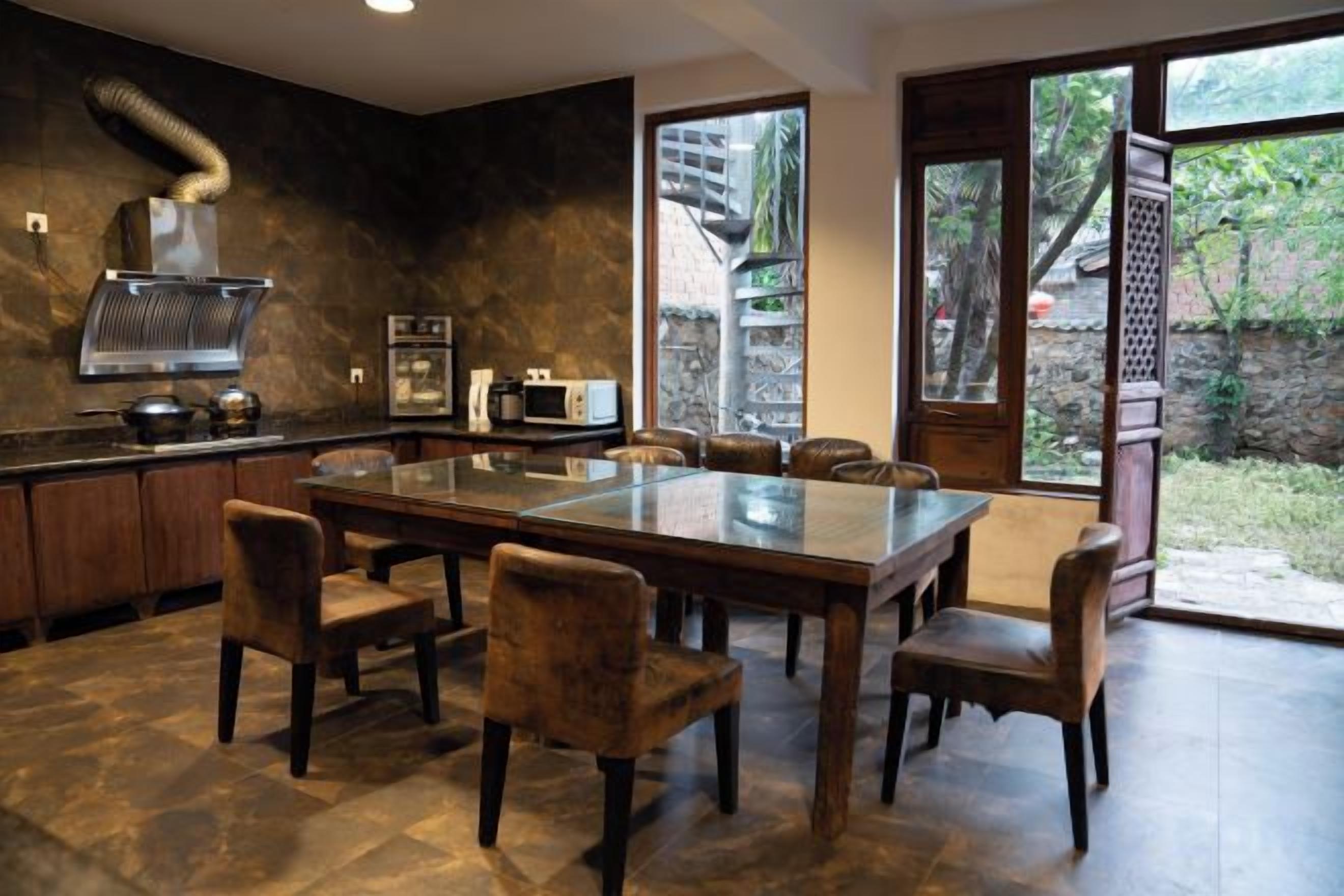 A modern kitchen with a large island, dark wood cabinetry, and a view of the outdoors.