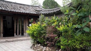 A traditional building with a tiled roof and a stone pathway leading to a wooden door. - Baisha No. 66 Post Station (Yulong)