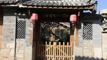 A traditional Chinese gate with a wooden fence, stone walls, and tiled roof.