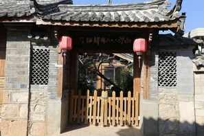 Una puerta tradicional china con cerca de madera, muros de piedra y tejado de tejas.