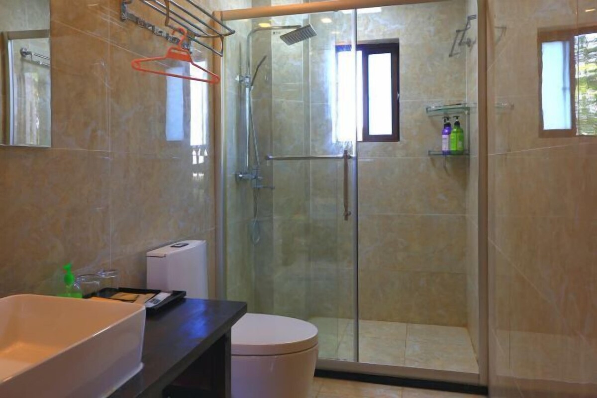 Un baño con ducha de vidrio, un lavabo blanco y un inodoro.