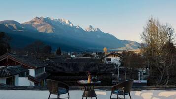 Una terraza con mesa y sillas con vistas a un paisaje montañoso.